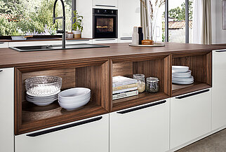 Eine stilvolle Küche mit weißen Schränken mit dunklen Holzdetails, organisierten Regalen und integrierten Geräten, die eine Mischung aus modernem Design und Praktikabilität hervorheben.