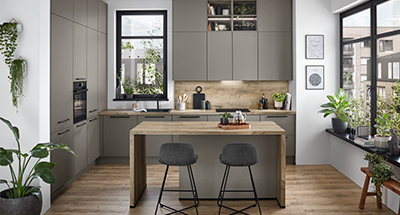 Moderne Kücheninnenräume mit eleganten grauen Schränken, Holzakzenten und Edelstahlgeräten, ergänzt durch natürliches Licht und Grün.