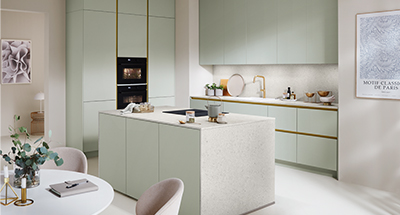 Elegantes, modernes Küchendesign mit gedämpften grünen Schränken, goldenen Akzenten, integrierten Geräten und minimalistischer Dekoration, das einen stilvollen und dennoch funktionalen Wohnraum präsentiert.